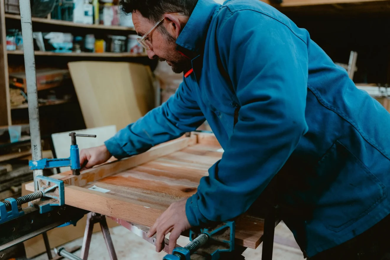 Artisan serrant un cadre de bois massif dans l’atelier Koadbooth de Plouguenast-Langast
