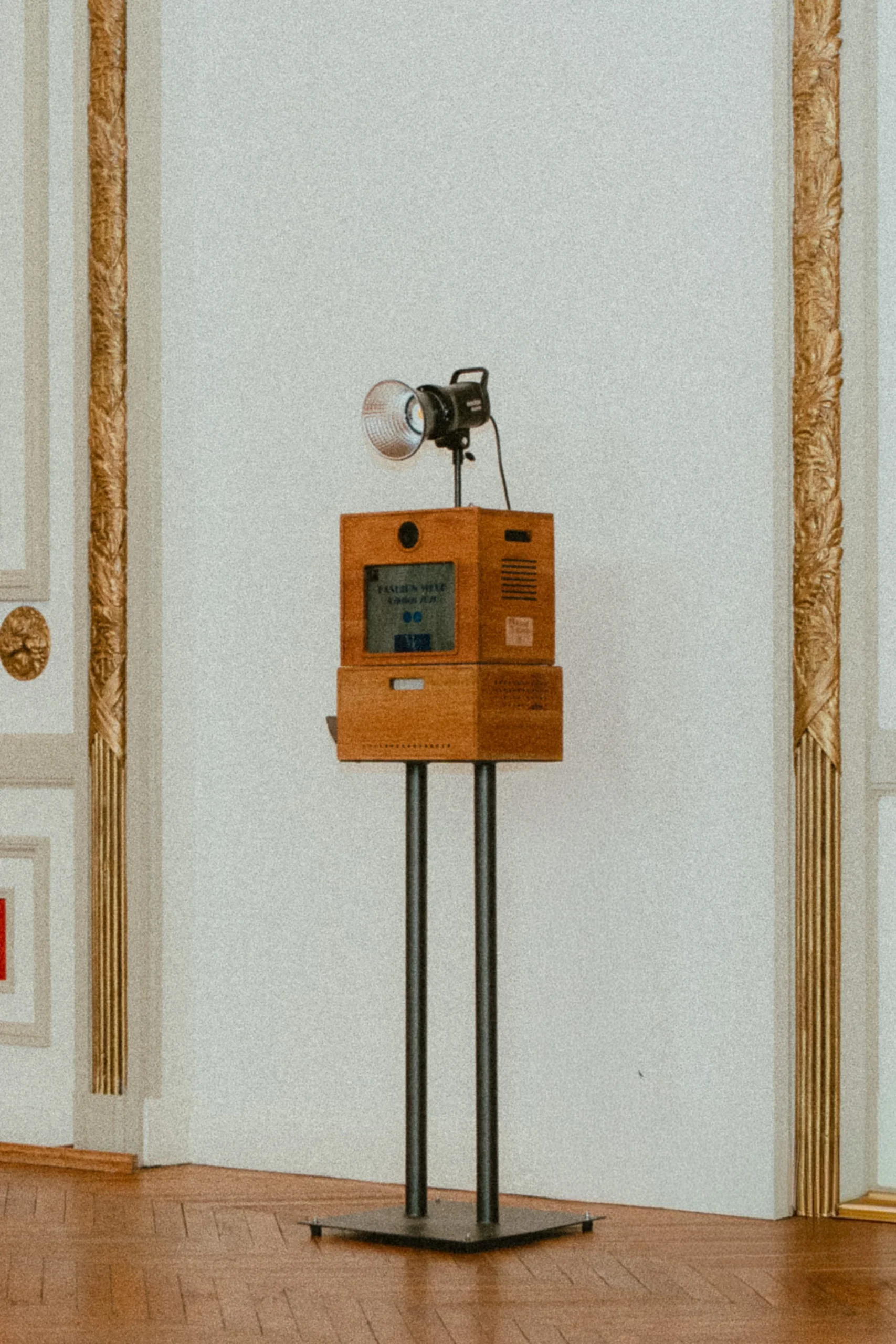 Un photobooth Koadbooth en bois massif sur pied, installé devant un mur clair à moulures