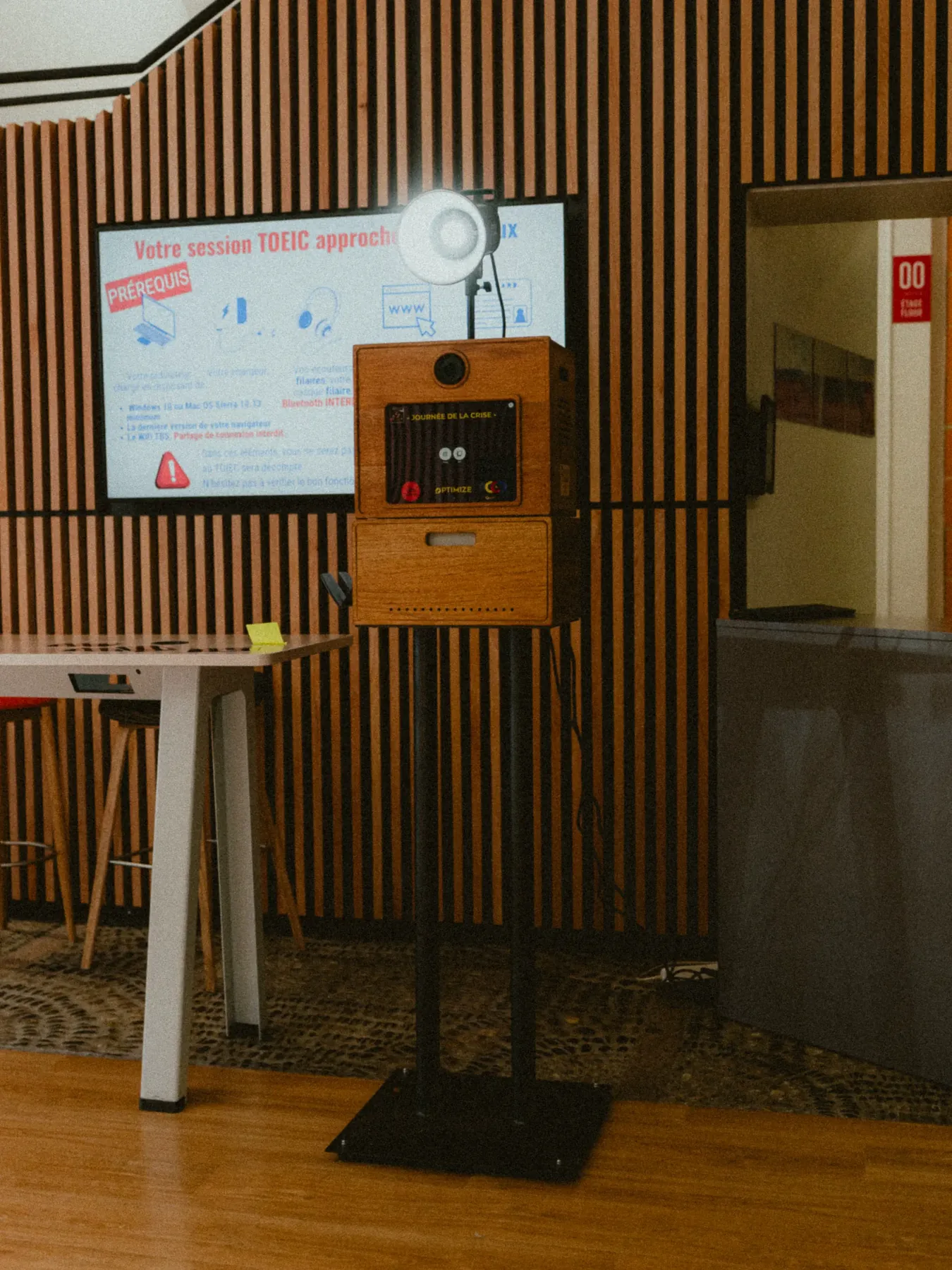 Photobooth Koadbooth installé lors d'un événement d'entreprise, devant un mur en tasseaux de bois