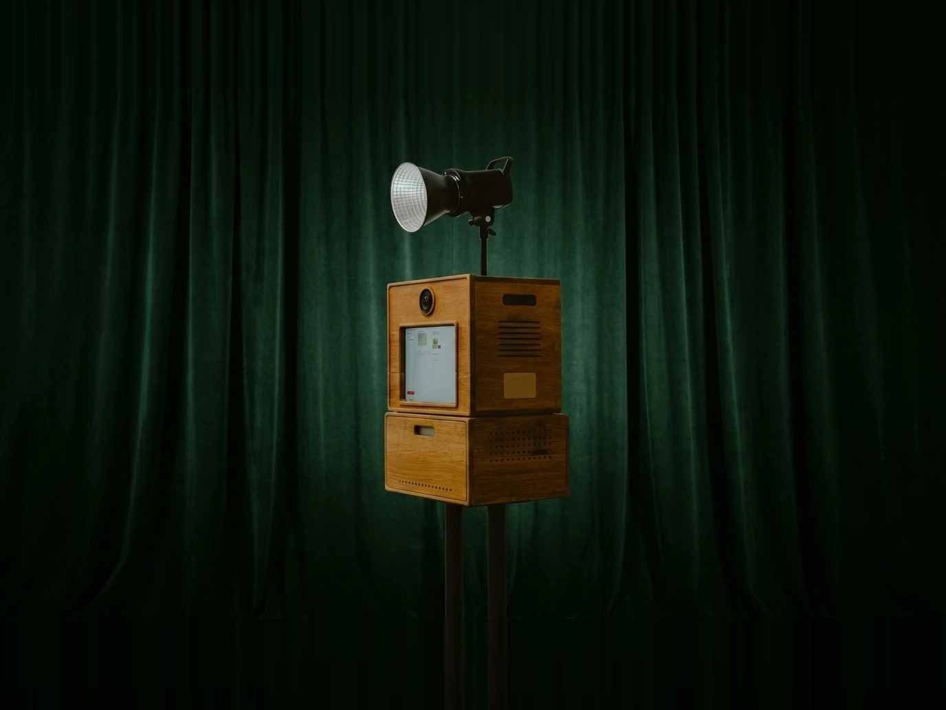 Photobooth Koadbooth Signature en bois massif, devant un rideau vert, avec son projecteur de studio