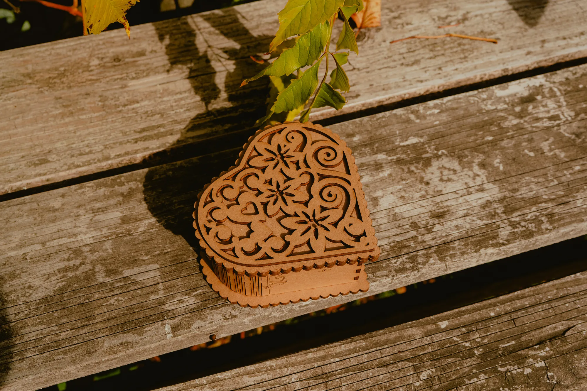 Boîte en bois en forme de cœur, au couvercle fleuri découpé en dentelle.