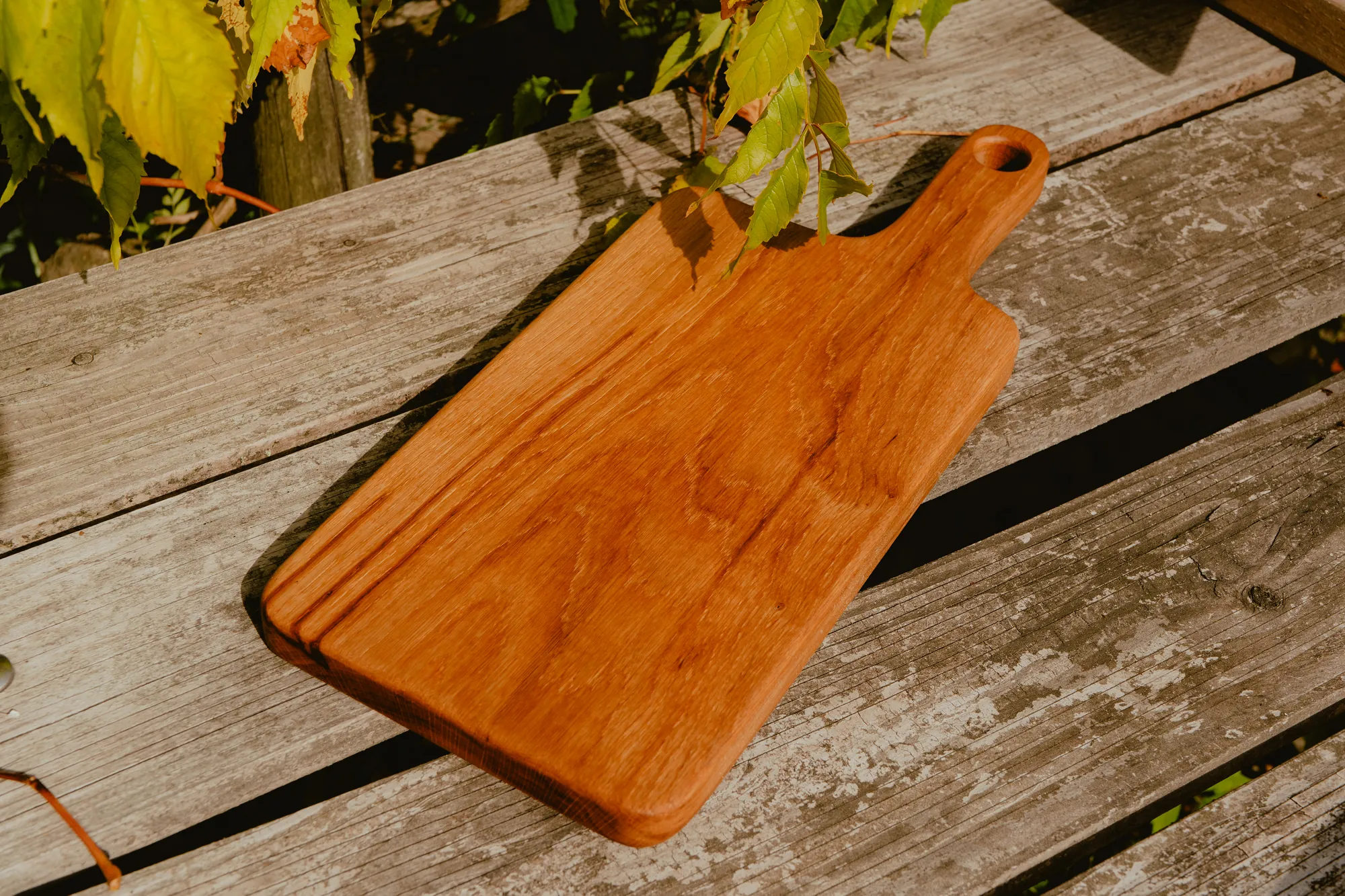 Planche de service longue en bois huilé, à poignée percée.